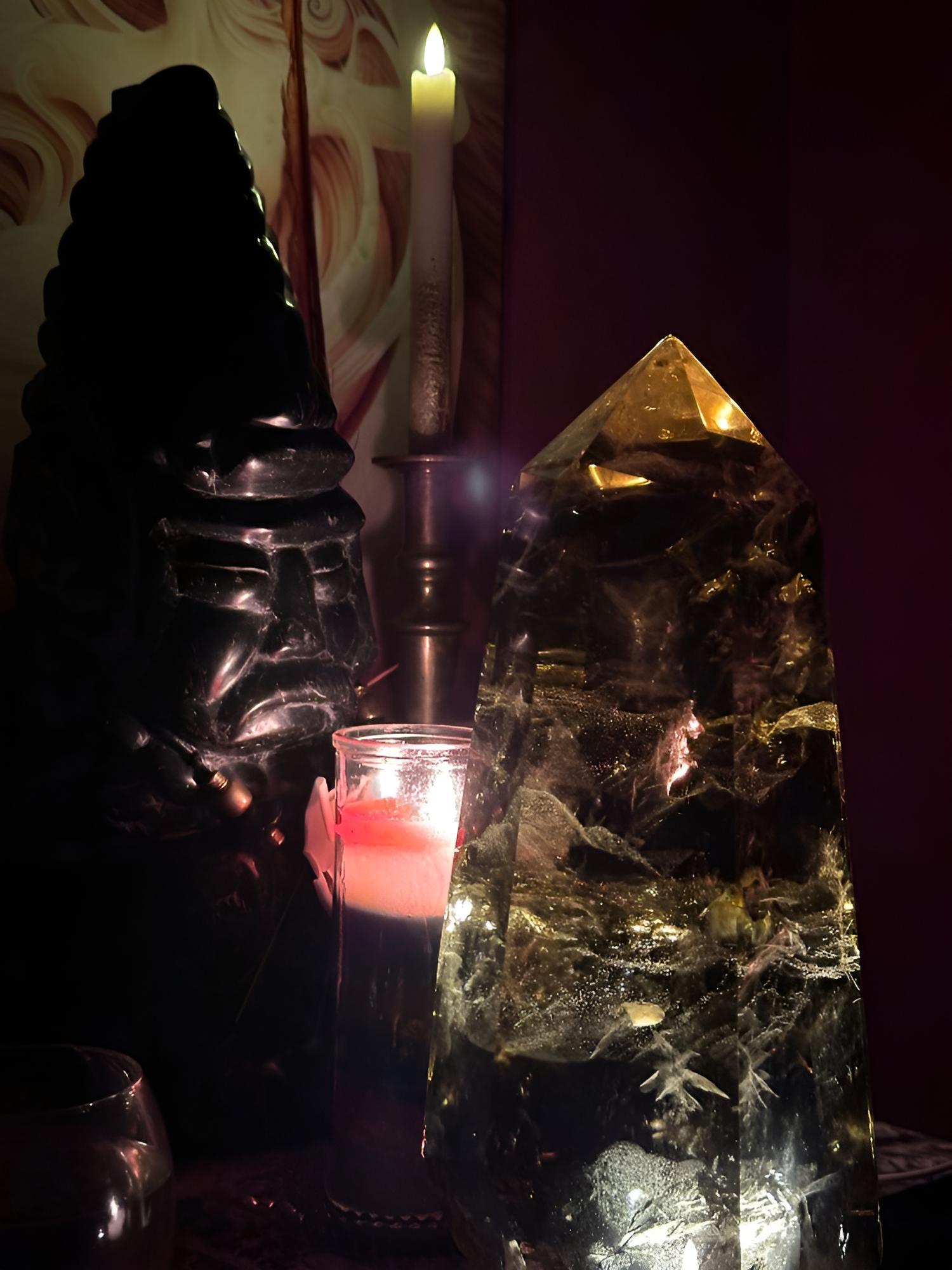Ein großer Bergkristall und eine schwarze Maya-Steinfigur im Kerzenlicht