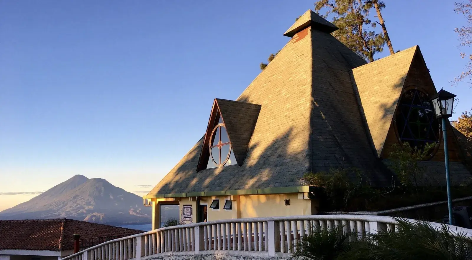 Ein Tempel des Zentrums mit pyramidenförmigem Dach im Morgenlicht, dahinter ein Vulkan