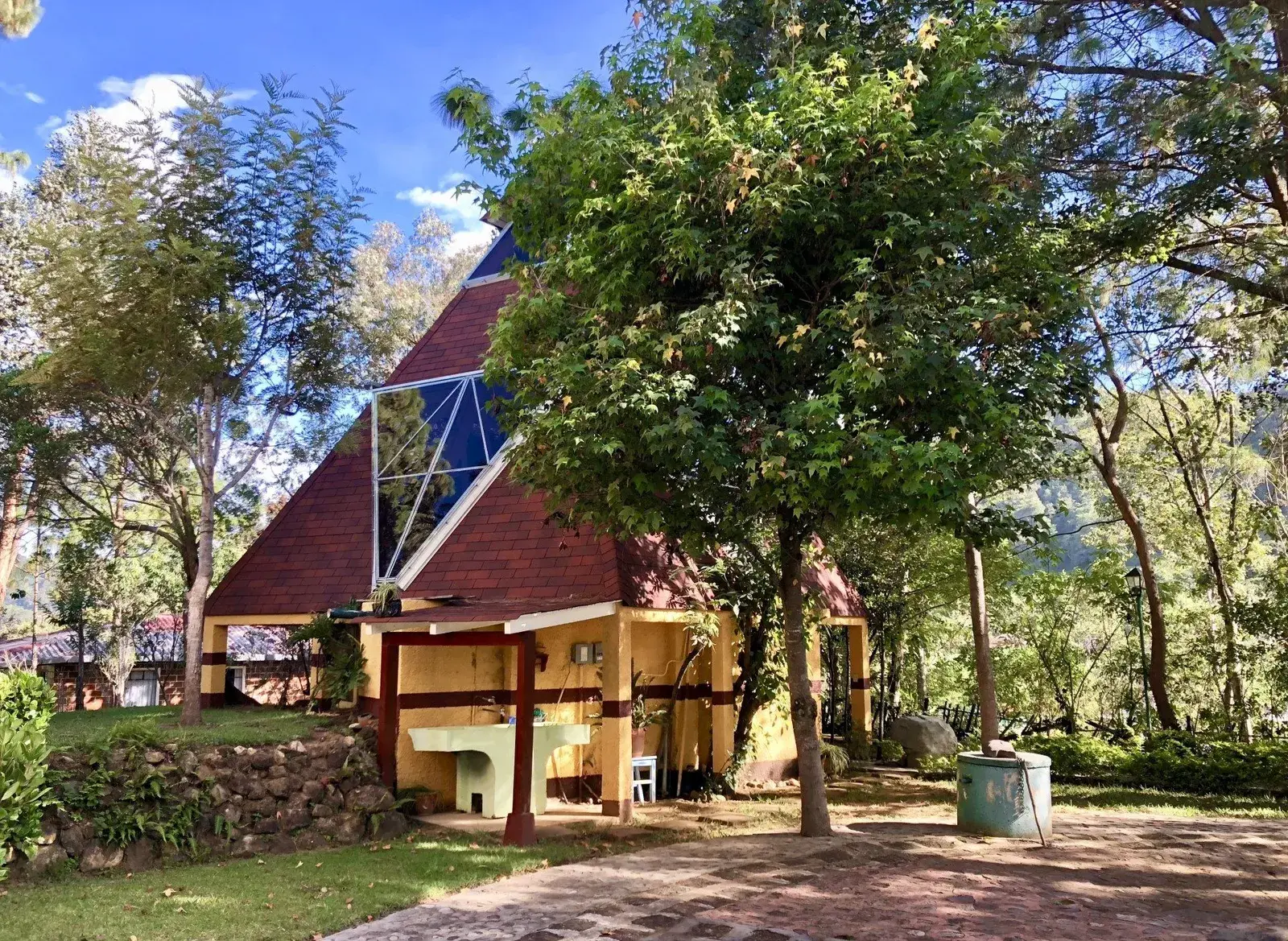 Der Tempel PORTÓN MUNDO der Sternenboten mit rotem Pyramidendach zwischen Bäumen